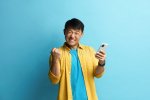 vincitore-con-smartphone-felice-uomo-asiatico-ha-alzato-il-braccio-gestendo-sì-un-estremamente...jpg